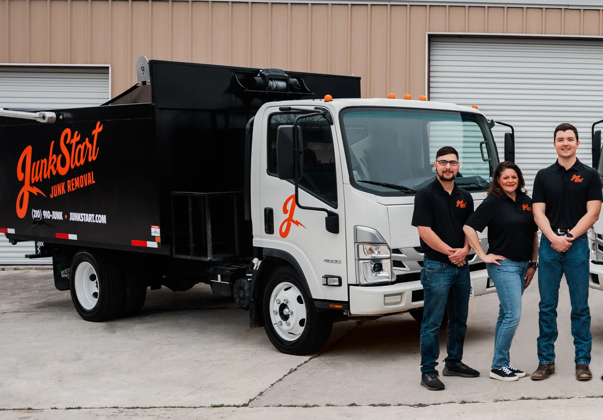 The JunkStart team proudly stands with their branded white and black junk removal truck.