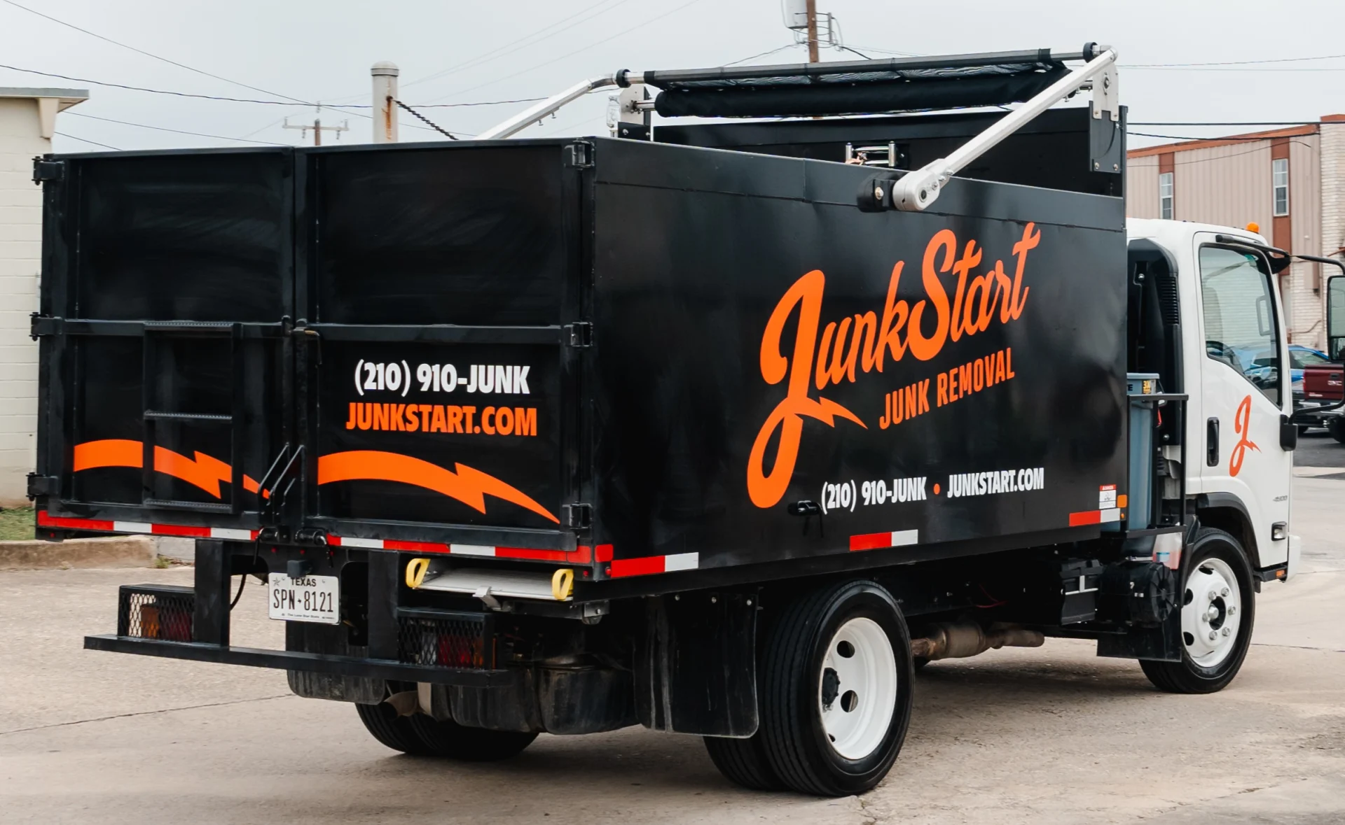 JunkStart's black and white junk removal truck displays orange branding and contact details. TITLE